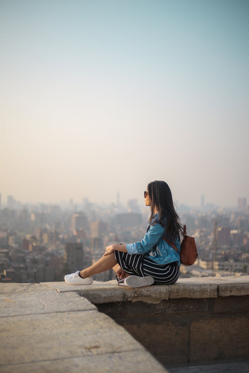 woman sitting on top of building s edge