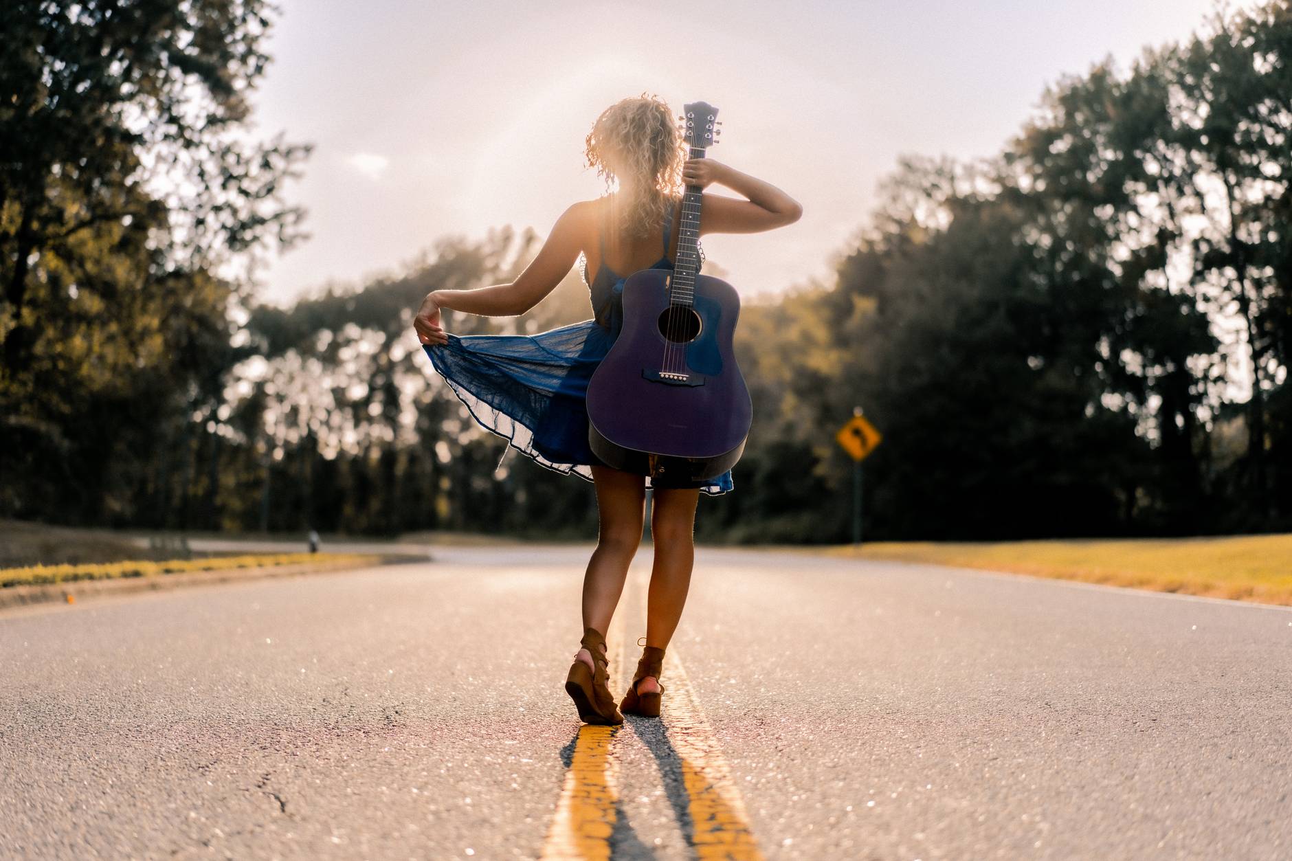 faceless joyful young female musician walking along road among park