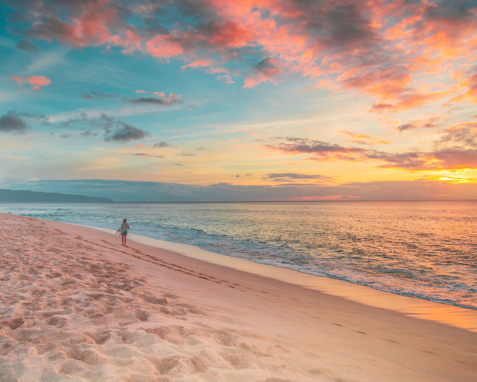 person walking on beach during sunset