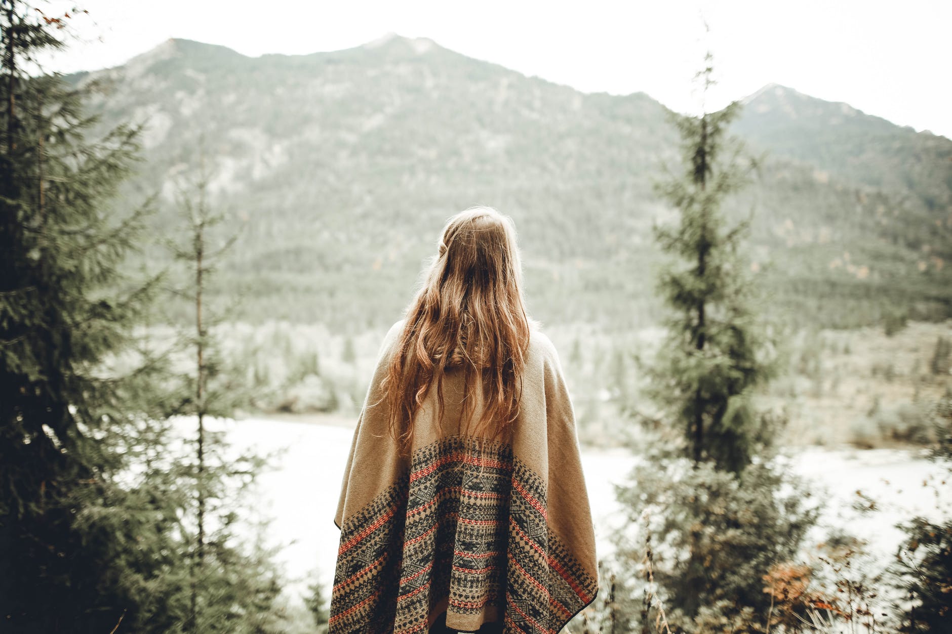 woman wearing brown poncho facing mountain